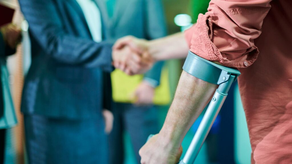 A man with crutches shaking hands with a lawyer regarding legal support in accident claims